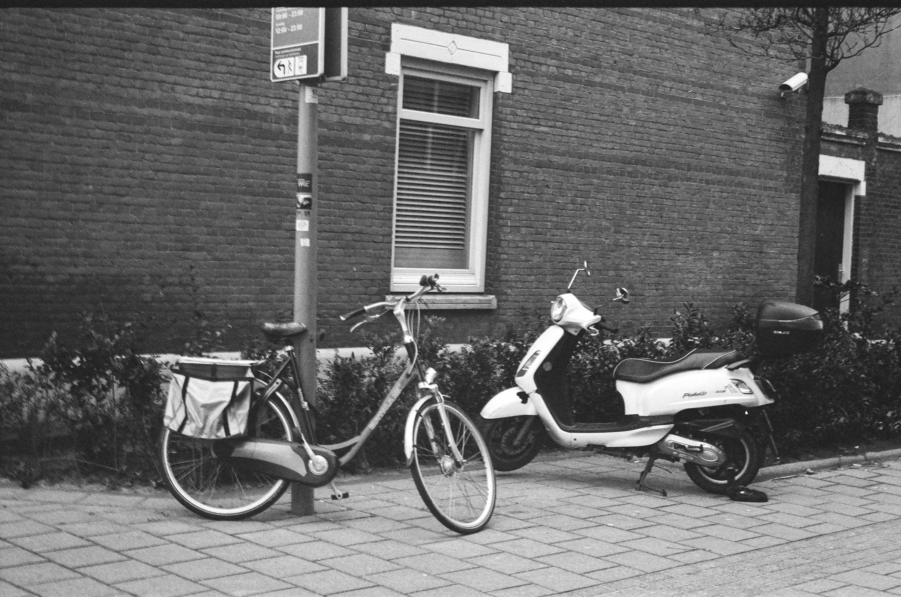 grayscale photo of a motorcycle parked beside a wall