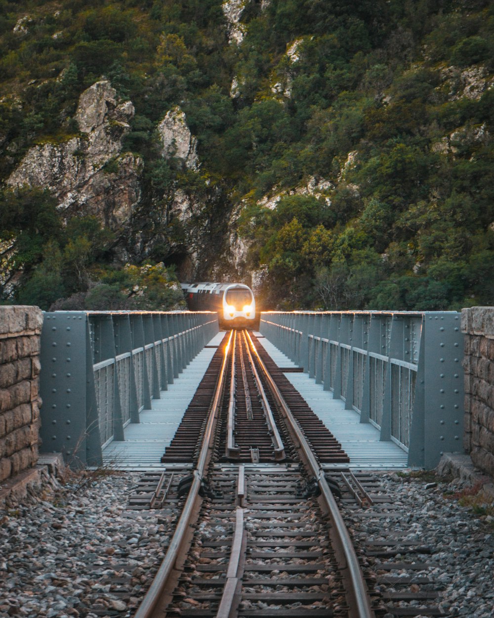 man in black jacket and blue denim jeans walking on train rail during daytime