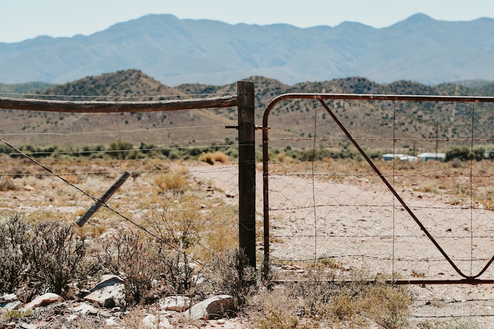 brown metal fence near green grass field during daytime