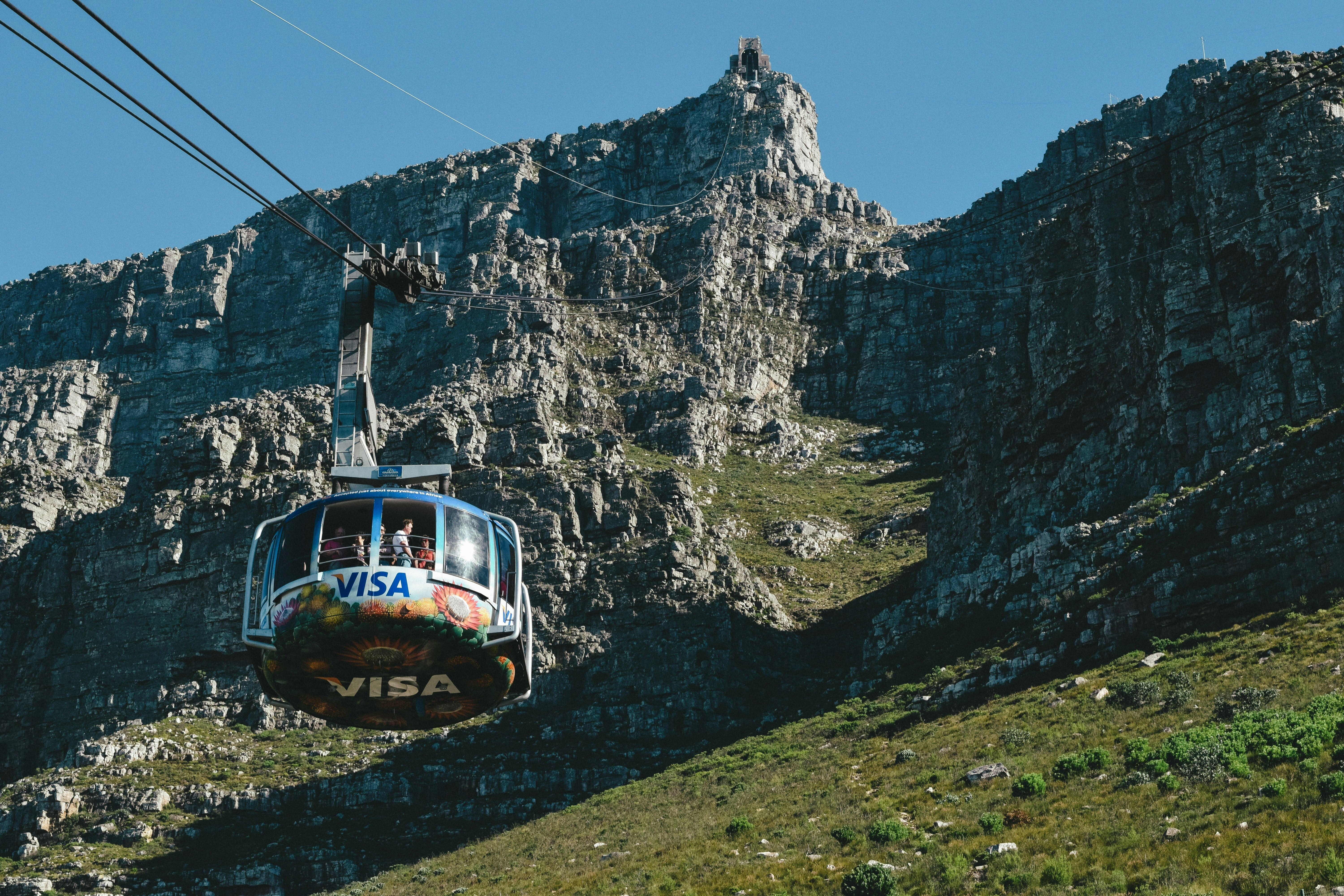 red and white cable car on green grass field near mountain during daytime