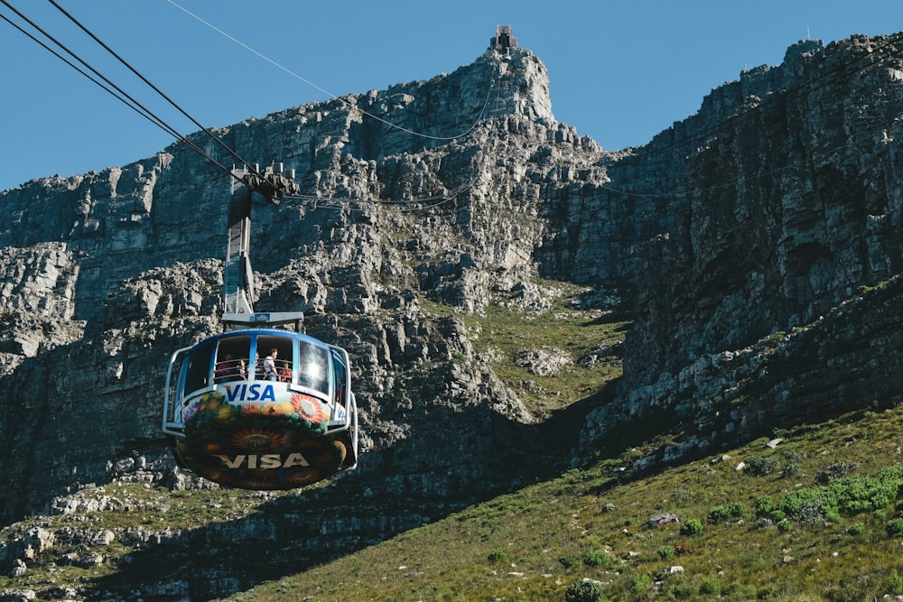 red and white cable car on green grass field near mountain during daytime