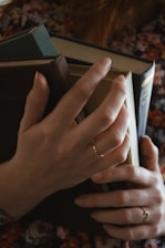 Close-up of hands gently holding a textured book cover with earthy tones and organic patterns.