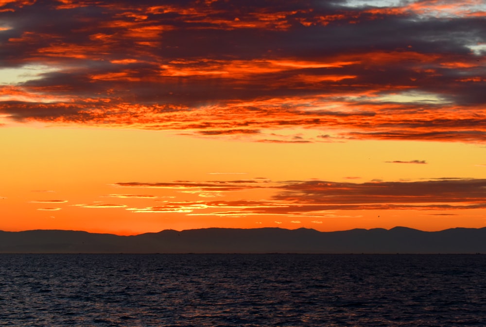 body of water under orange and blue sky during sunset