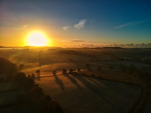A serene aerial view of lush green plots and natural landscapes at sunrise.