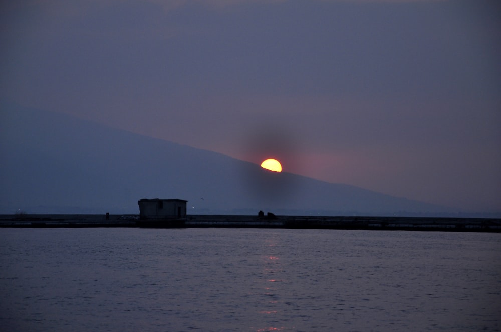 silhouette of building near body of water during sunset