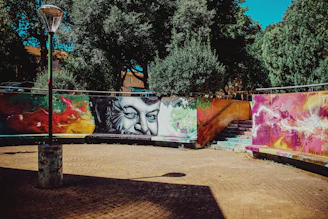Vibrant photo of a Black artist painting a colorful mural in an urban street setting.