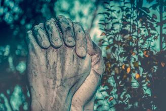 Hands holding a detailed stone sculpture reproduction against a backdrop of a softly lit gallery space.