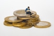 guy sitting on a bunch of gold coins as preview for blog post about debunking common gold ira myths