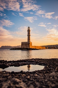 brown and white lighthouse near body of water during sunset