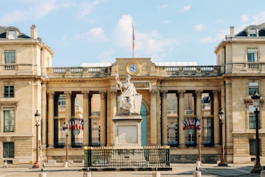 white concrete building with statue under white clouds during daytime