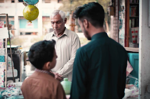 Couple exchanging a friendly conversation with the shopkeeper under soft orange and blue tones.