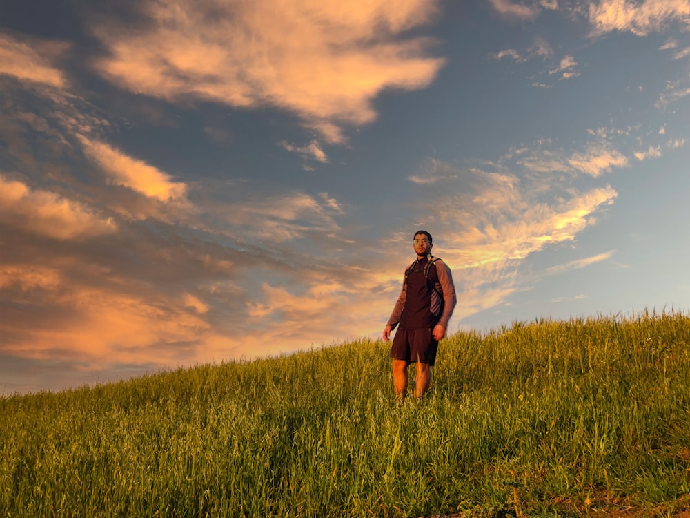 woman in black jacket standing on green grass field under cloudy sky during daytime