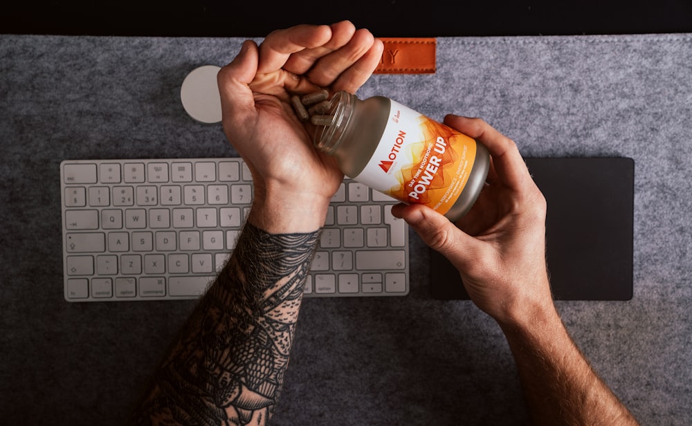 person holding orange and white labeled plastic bottle