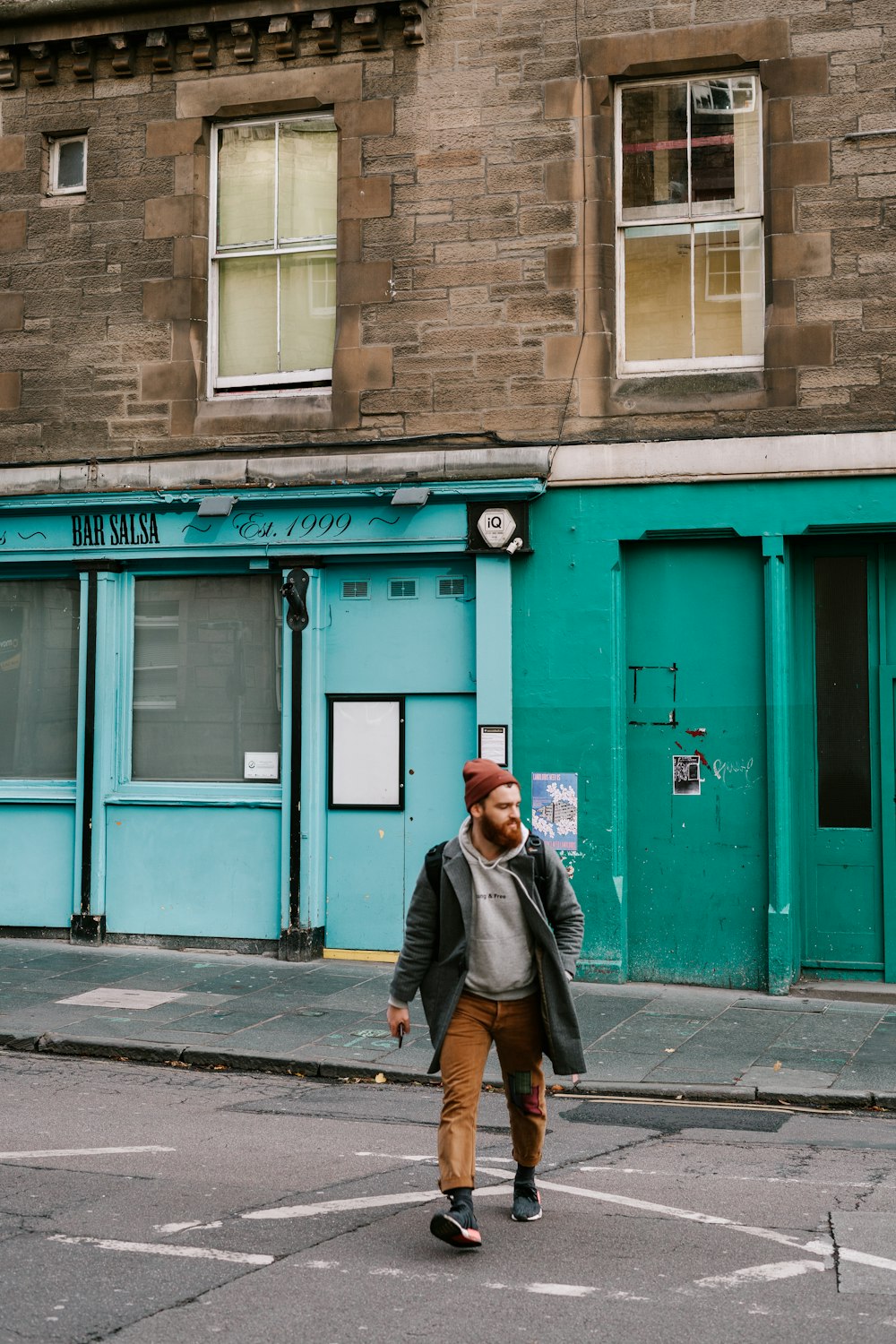 man in green jacket walking on sidewalk during daytime