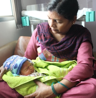 woman in red and black long sleeve shirt holding baby