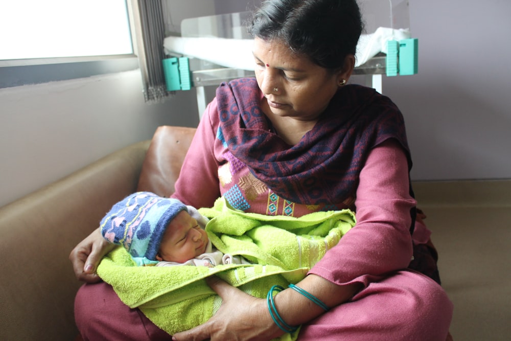 woman in red and black long sleeve shirt holding baby