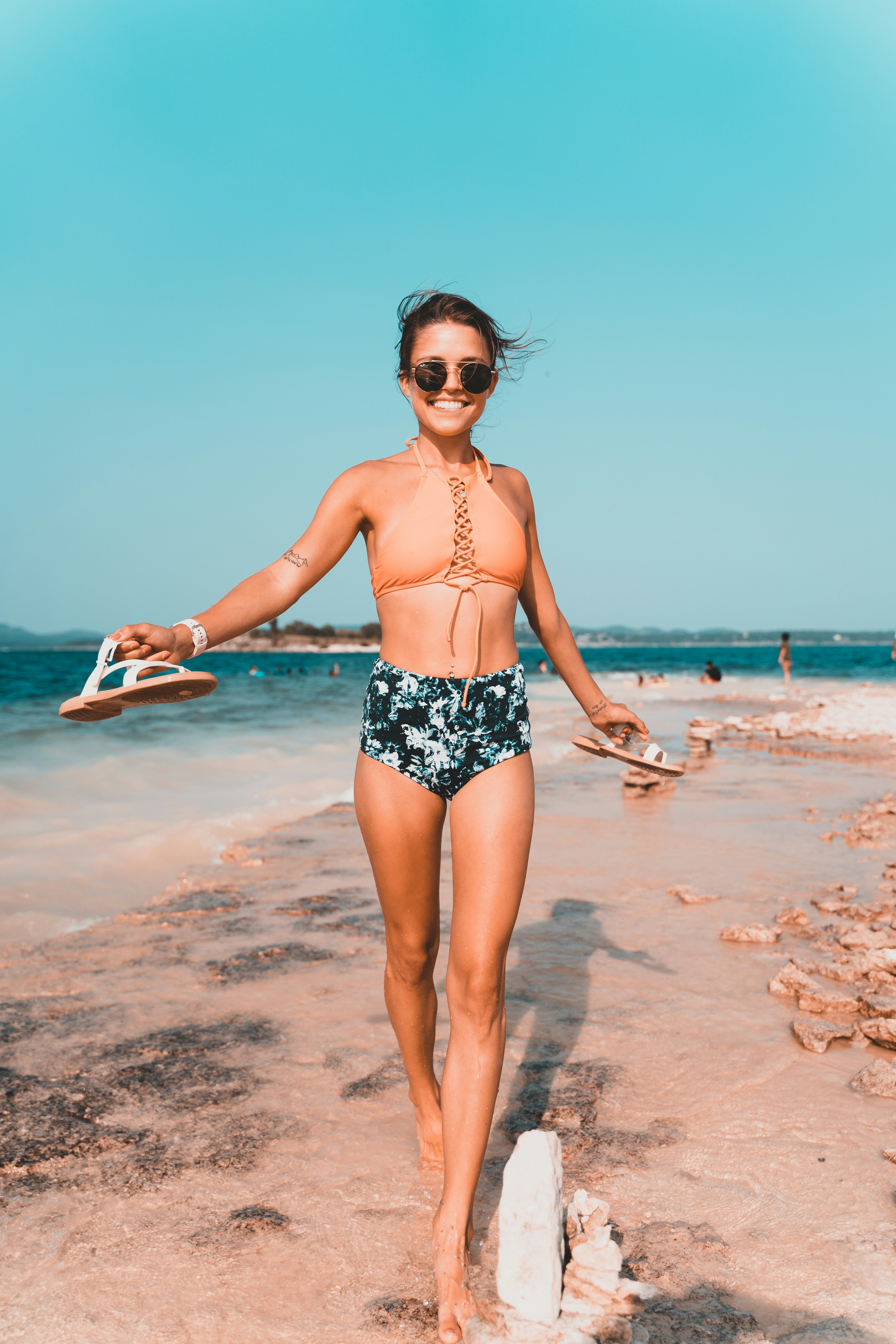 woman-in-black-and-white-floral-bikini-standing-on-beach-during-daytime