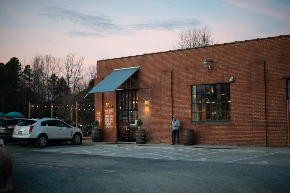 brown brick building near white car during daytime