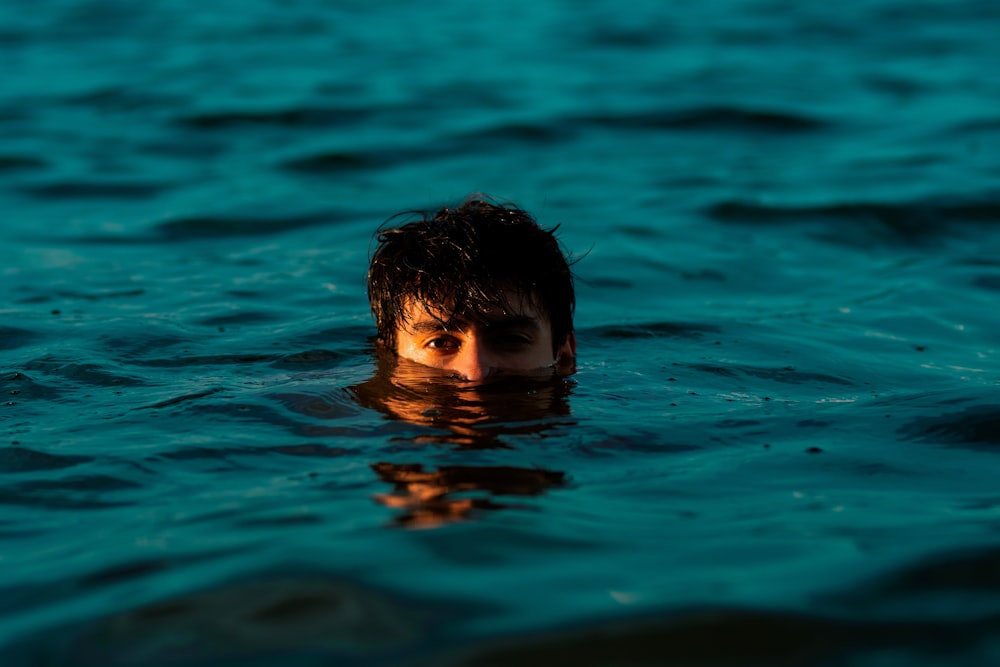 boy swimming on water during daytime