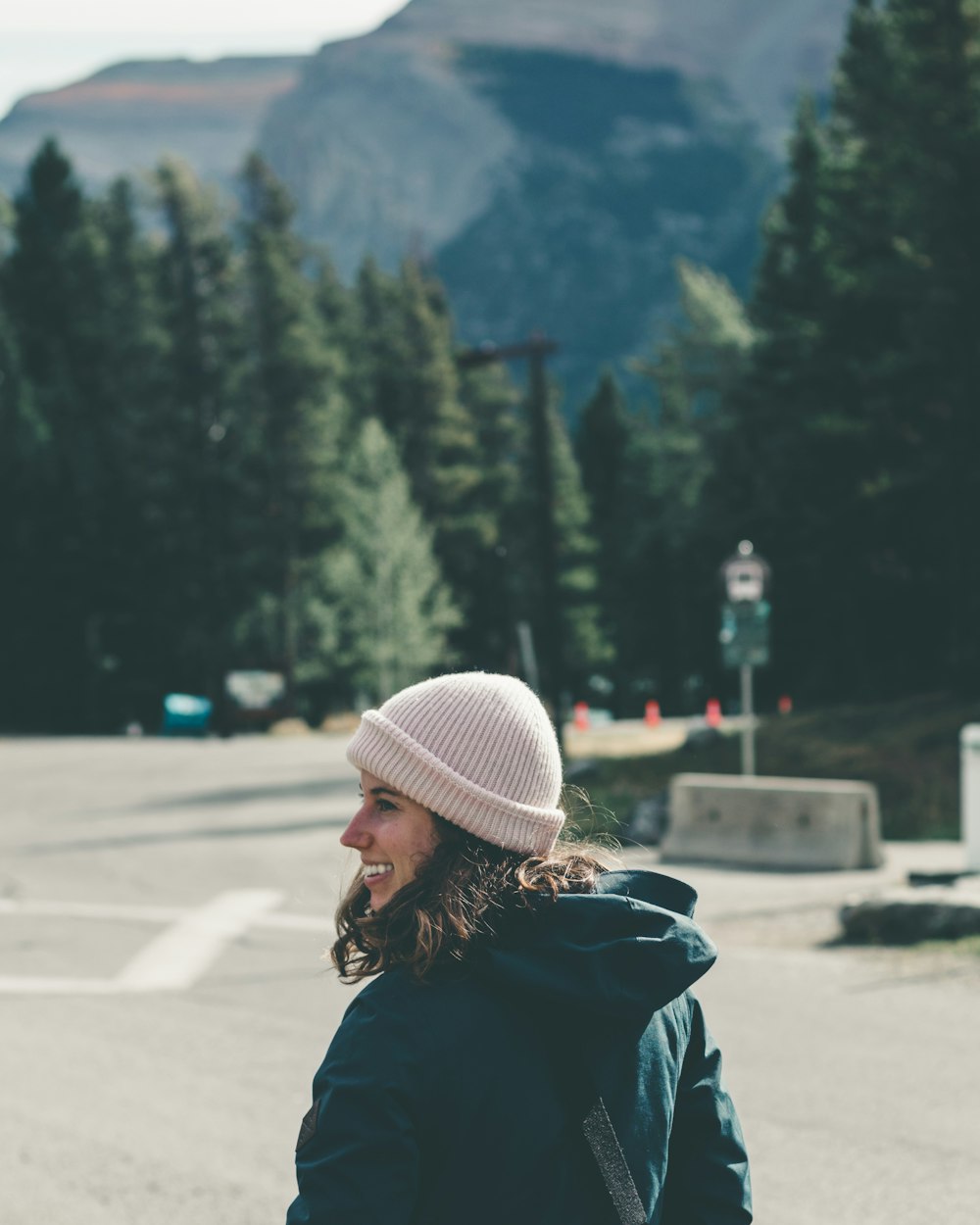 woman in black jacket and white knit cap standing on road during daytime