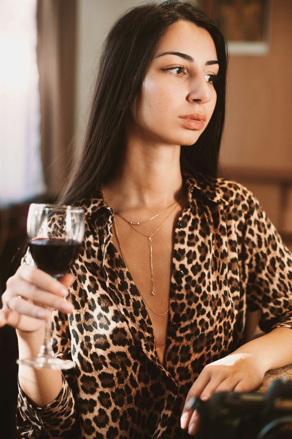 Frau in braun-schwarzem Langarmshirt mit Leopardenprint mit klarem Weinglas