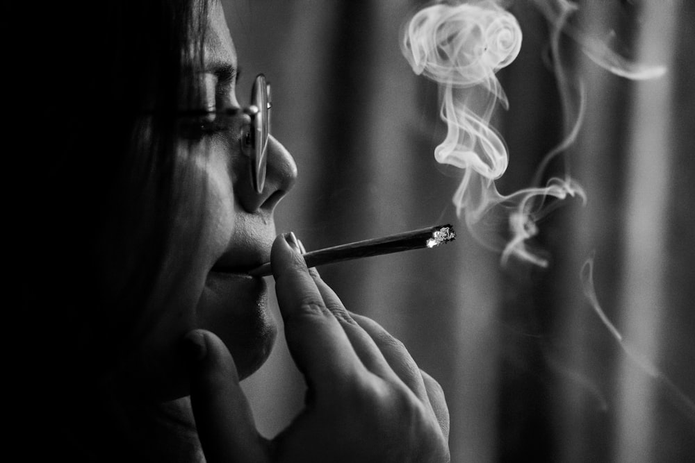 그레이스케일 사진에서 담배를 피우는 여자