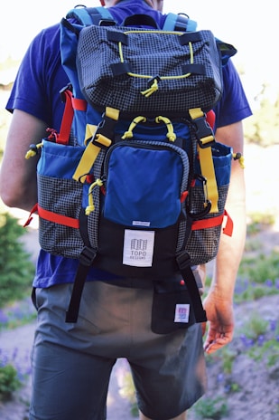 man in red t-shirt carrying black and orange backpack
