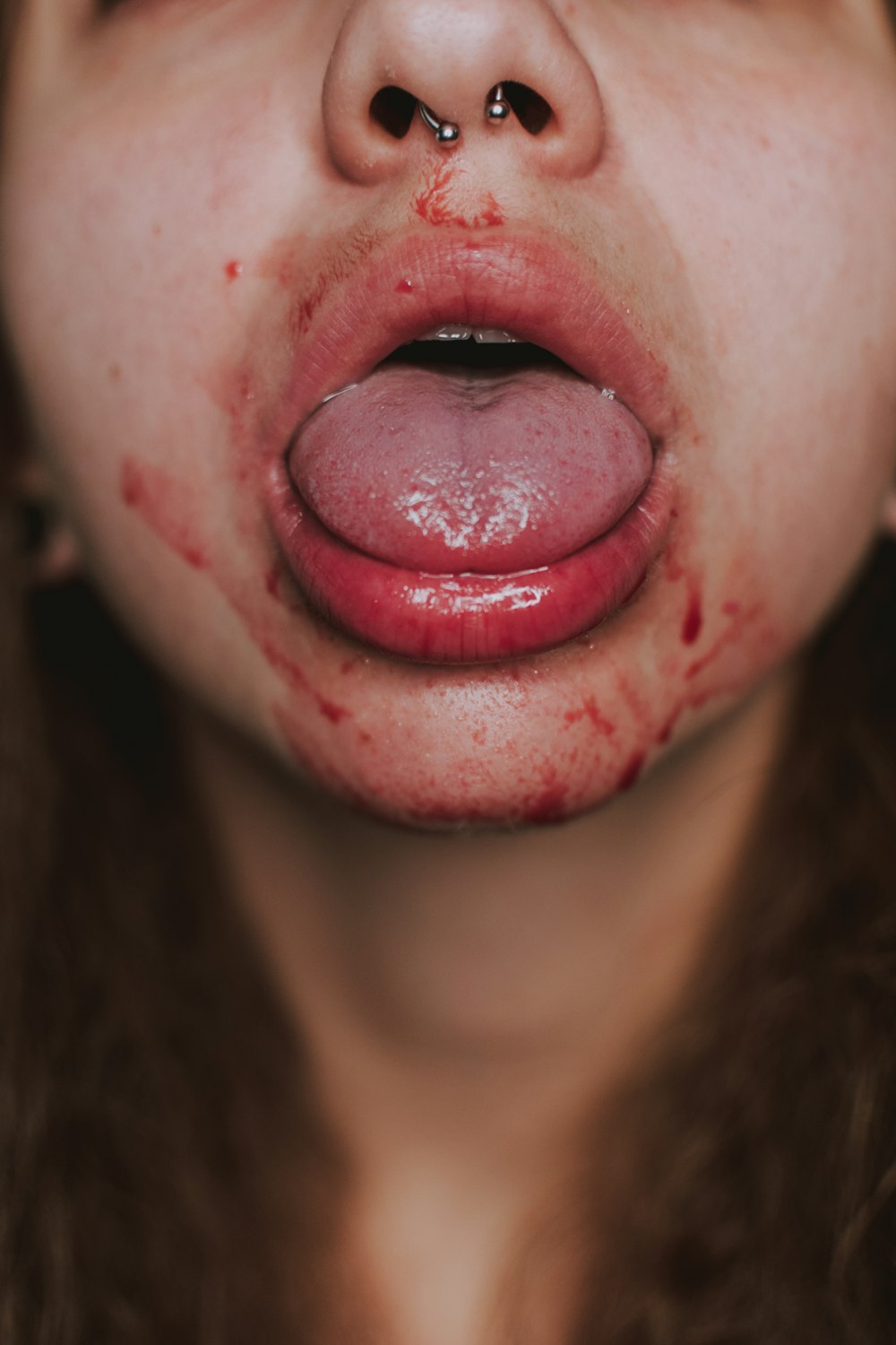 Mujer con lápiz labial rojo mostrando su lengua