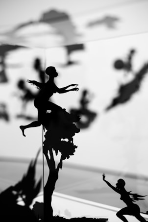 Silhouette images depict figures engaging in various dynamic poses, some appearing to be flying or climbing. The background is blurred, enhancing the contrast between the black figures and the lighter backdrop, giving a sense of motion and mystery.