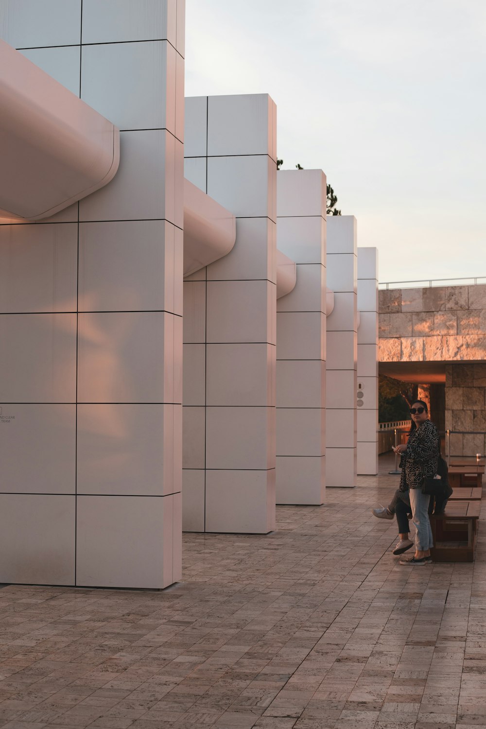 man in black jacket standing beside white concrete building during daytime