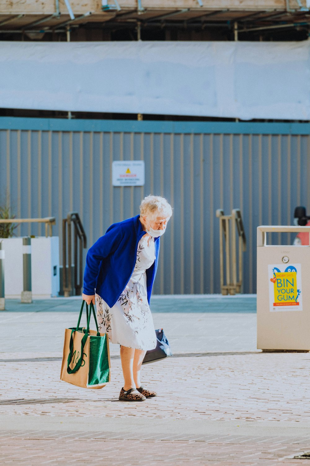 Femme en blazer bleu et robe blanche tenant un sac à main vert