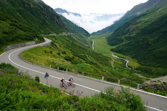 Cyclists riding along a rugged mountain trail with panoramic Himalayan views.