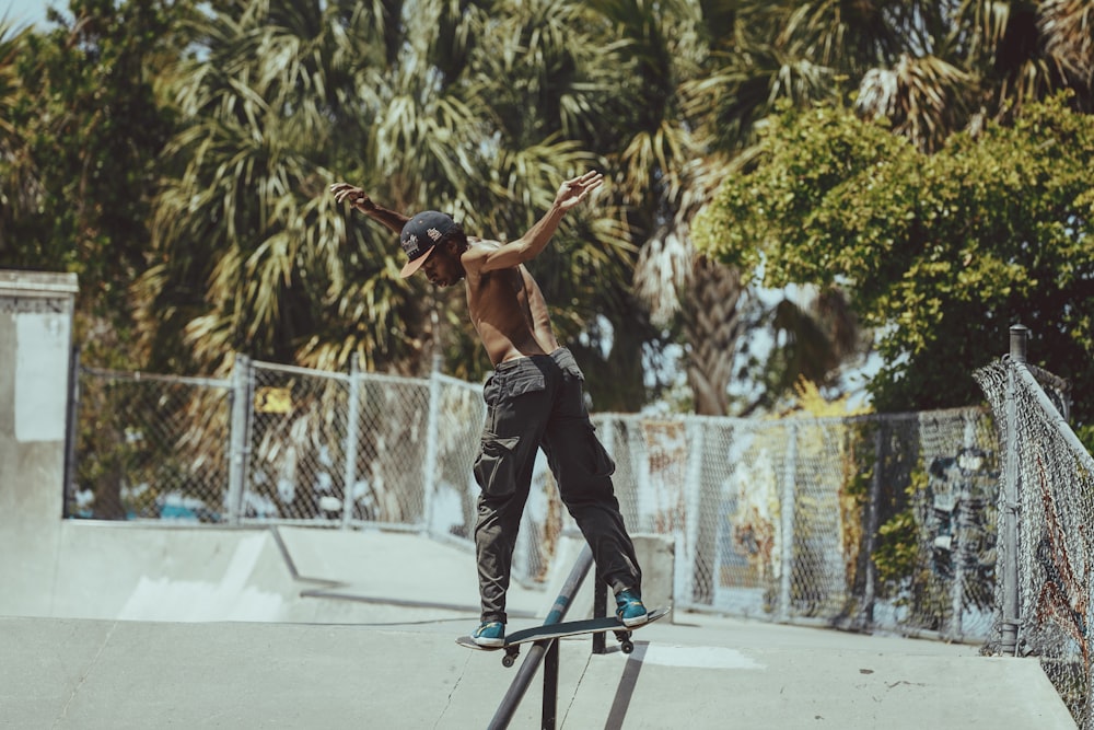 man in black tank top and black pants doing skateboard stunts