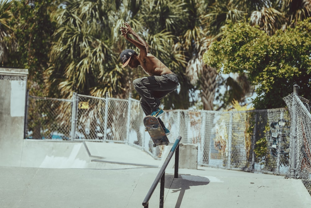 man in black jacket and black pants doing skateboard stunts on black and blue skateboard ramp