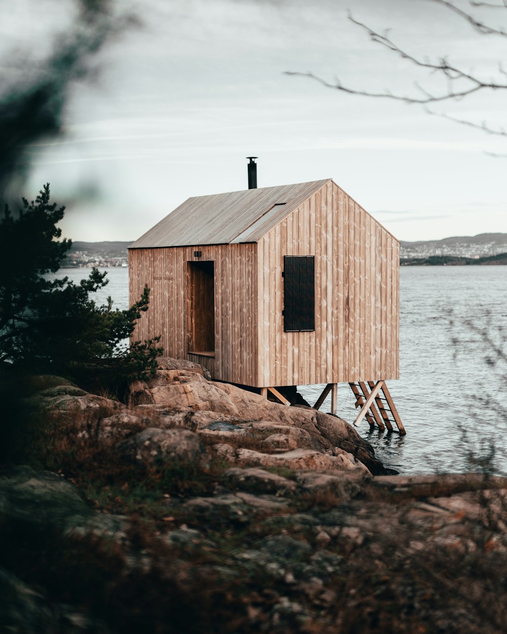 casa de madeira marrom na rocha marrom perto do corpo de água