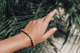 A hand wearing a grainaura bracelet, showing the smooth finish and natural wood texture
