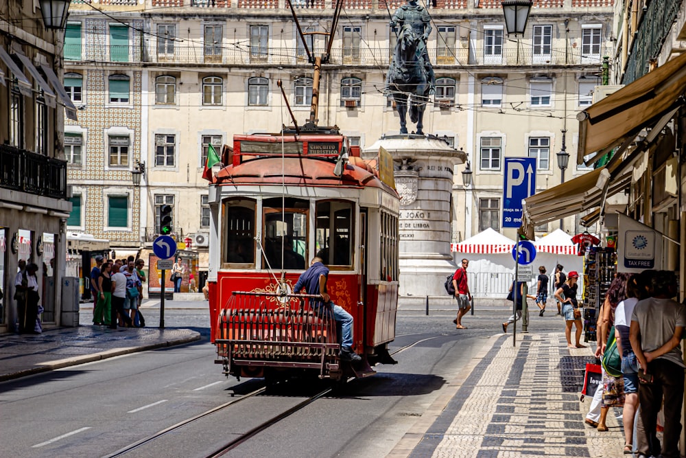 red tram on road near white concrete building during daytime