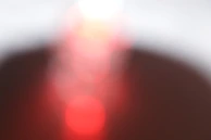 Soft focus image of a golden spiral interacting with crimson light gradients on creamy white.