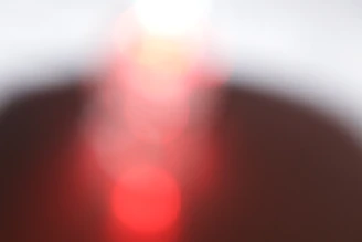 Soft focus image of a golden spiral interacting with crimson light gradients on creamy white.