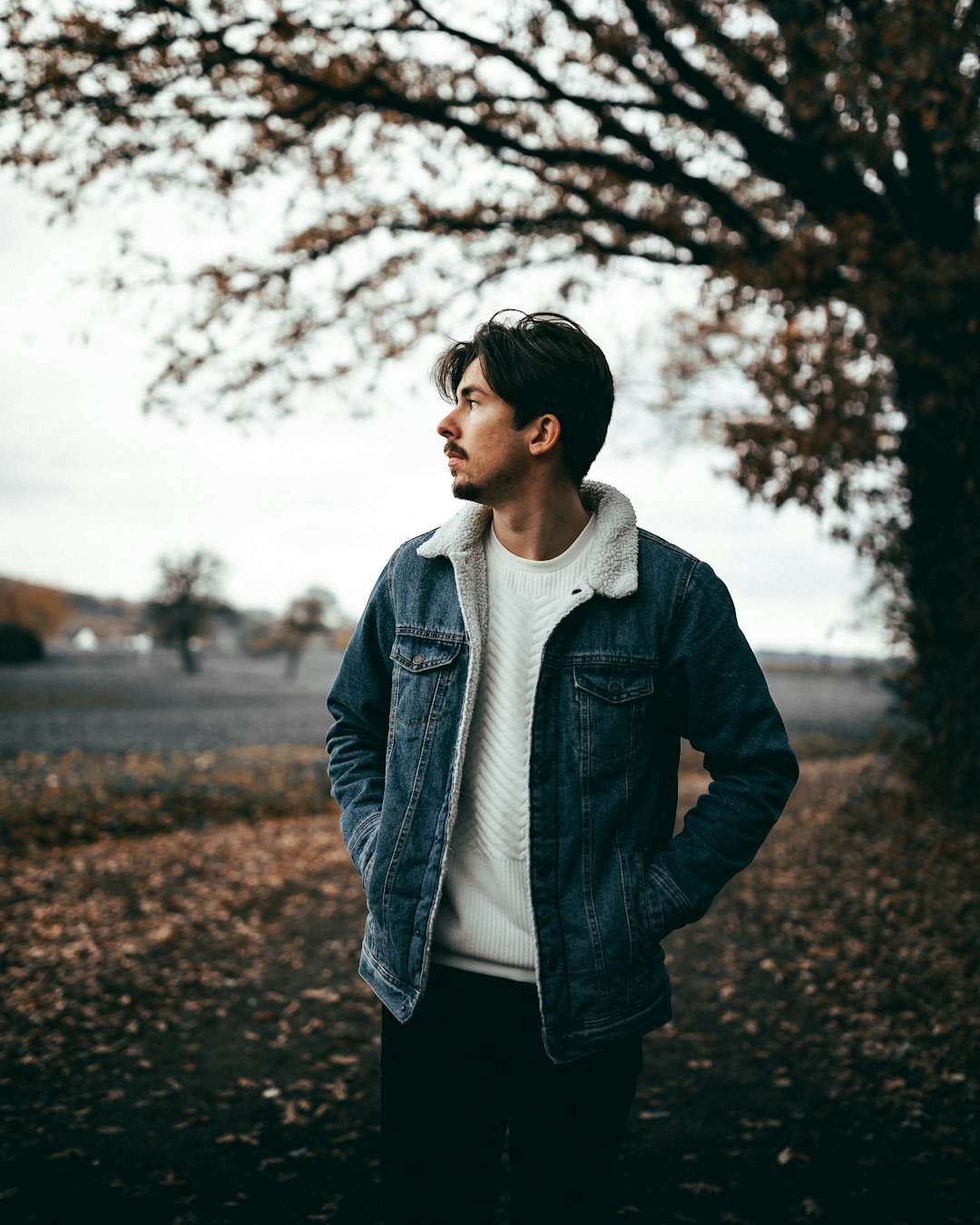 man in black leather jacket standing on road during daytime