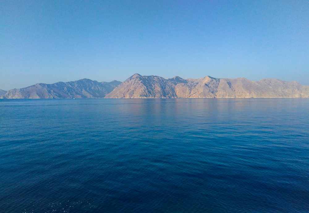 body of water near mountain during daytime