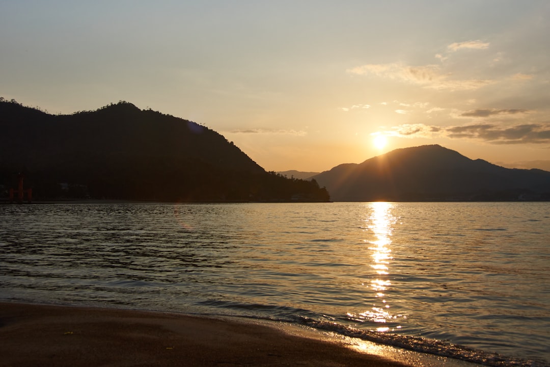 silhouette of mountain near body of water during sunset