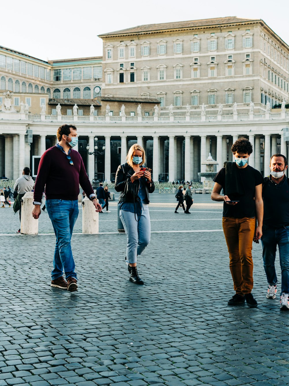 3 men and woman walking on street during daytime