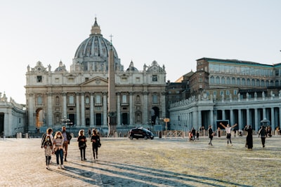 people walking near white concrete building during daytime vatican city google meet background
