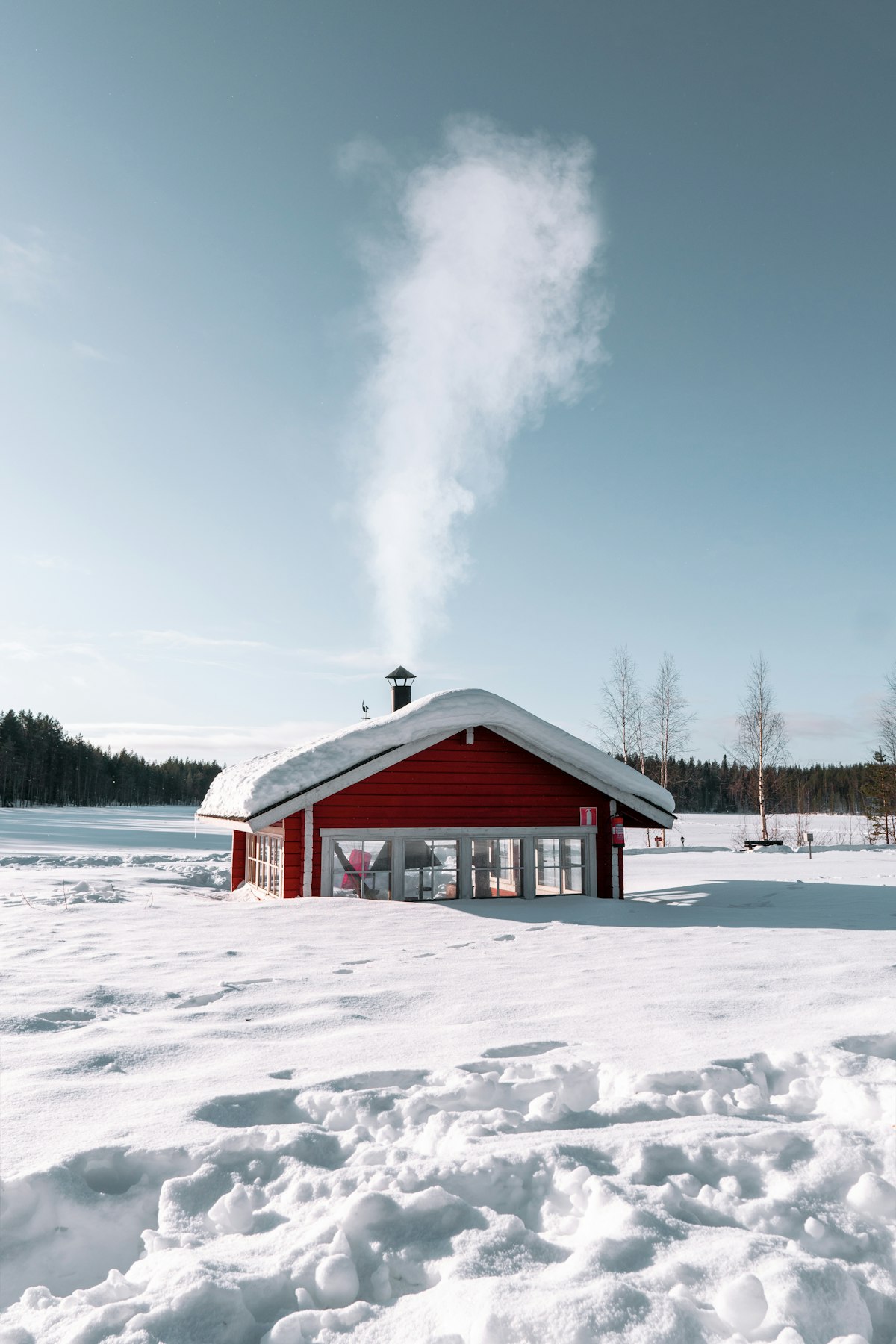 Red and white wooden house in deep snow in Lapland