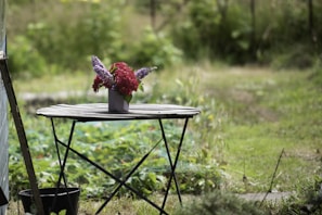 A delicate metal flower-shaped garden table with a weathered patina, set on a stone patio.