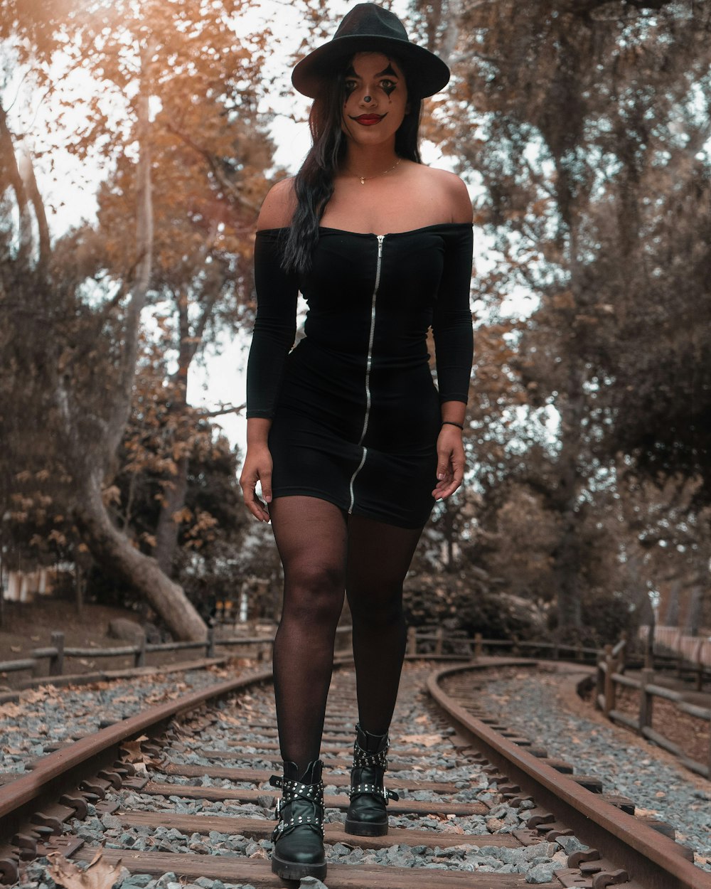 woman in black long sleeve dress standing on train rail during daytime