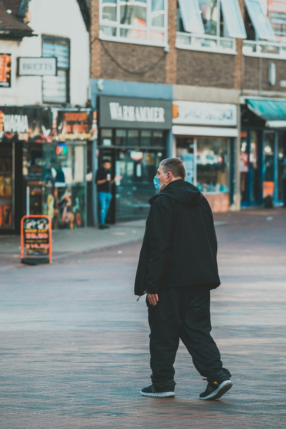 man in black coat walking on sidewalk during daytime