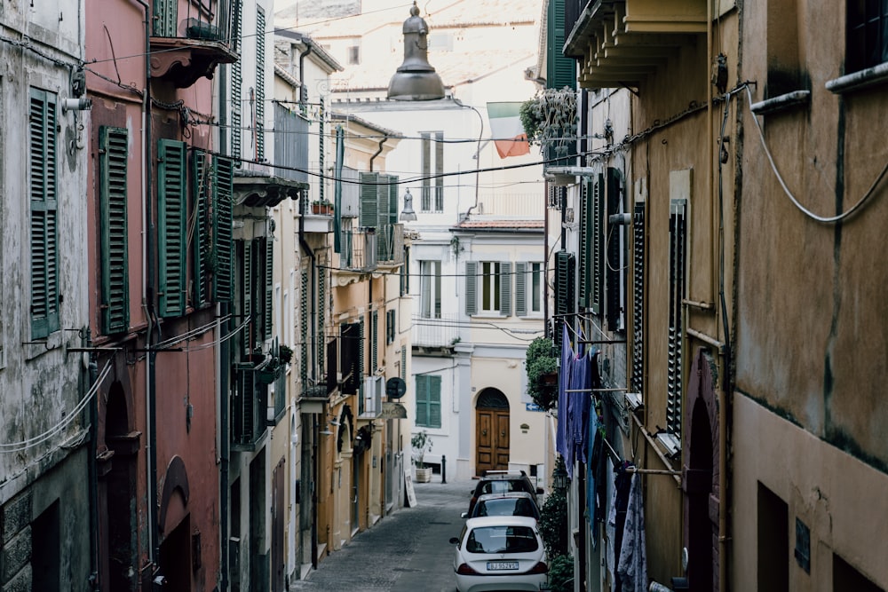 cars parked on street between buildings during daytime