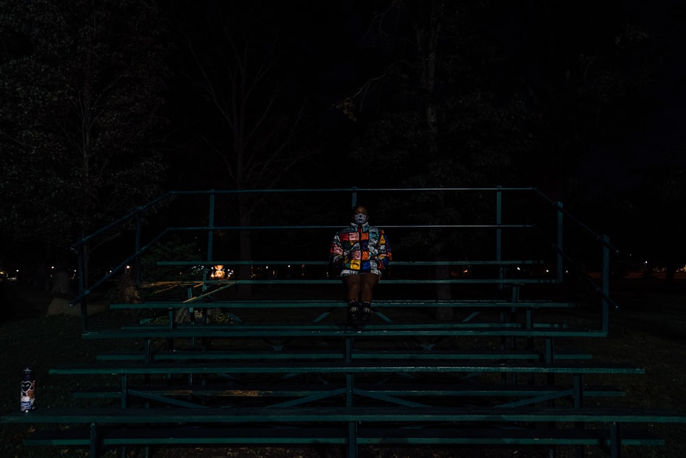 man in black jacket and black pants standing on black metal railings during night time